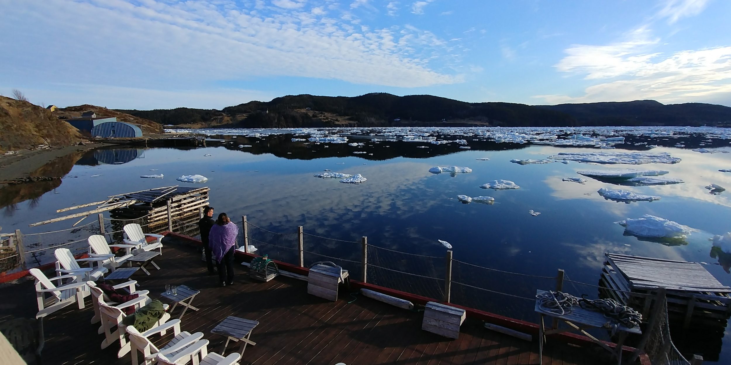 White deck chairs overlook an icy cove in Trinity