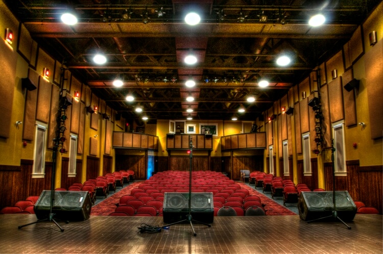 looking out from the stage of the Garrick Theatre. A mic in the centre of the stage, red chairs and the lights are up.